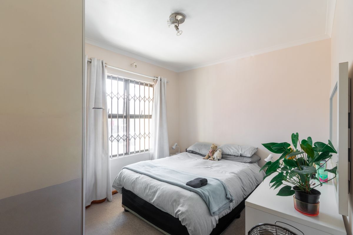 A standard bedroom featuring a window with a security gate and neutral wall finishes.