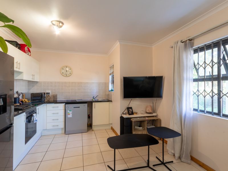 Open-plan kitchen and living area featuring tiled flooring, built-in cabinetry, and a functional kitchen layout with integrated oven and hob.