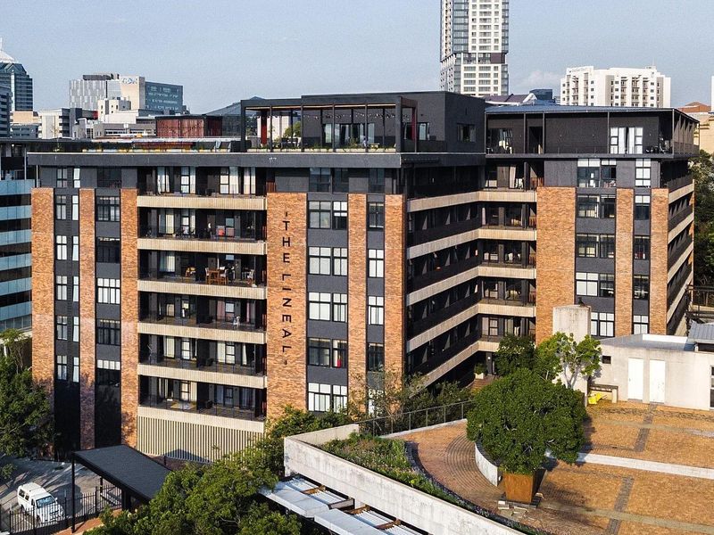 Aerial view of The Lineal apartment complex, showcasing its modern brick and dark metal facade, private balconies, and rooftop terrace area.