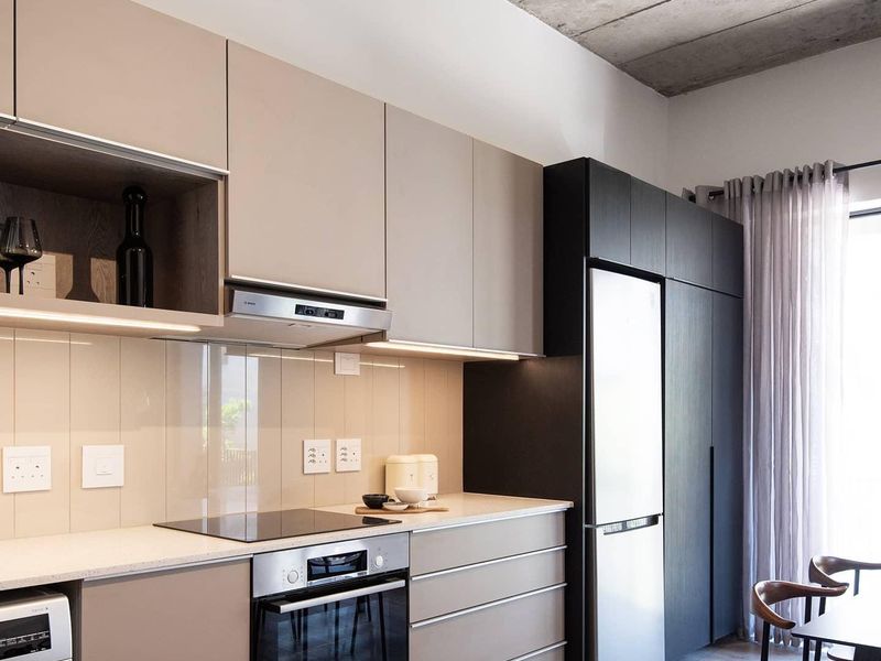 Modern kitchen featuring sleek handleless cabinetry, stone countertops, glass splashback, integrated appliances, and a striking exposed concrete ceiling.