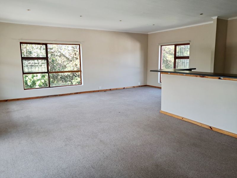 Spacious open-plan living area featuring neutral walls, carpet flooring, recessed lighting, and a built-in breakfast bar counter.
