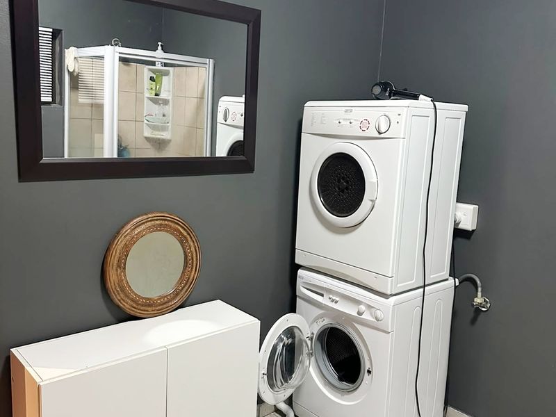 A functional laundry area featuring tiled flooring, plumbing connections for appliances, and dark painted walls.