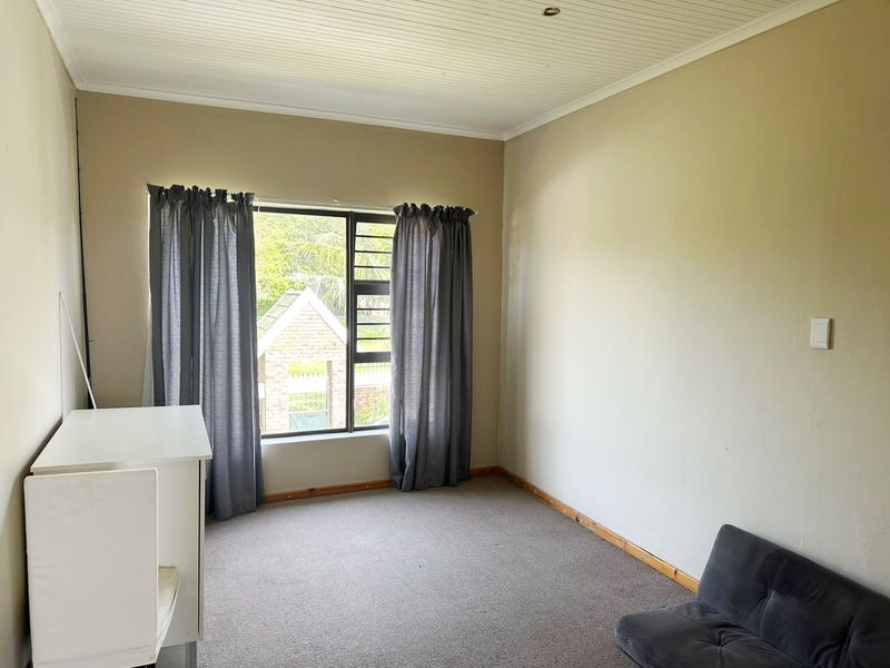 A bedroom featuring a beadboard ceiling, carpeted flooring, and an aluminium window frame, offering a neutral canvas for potential updates.