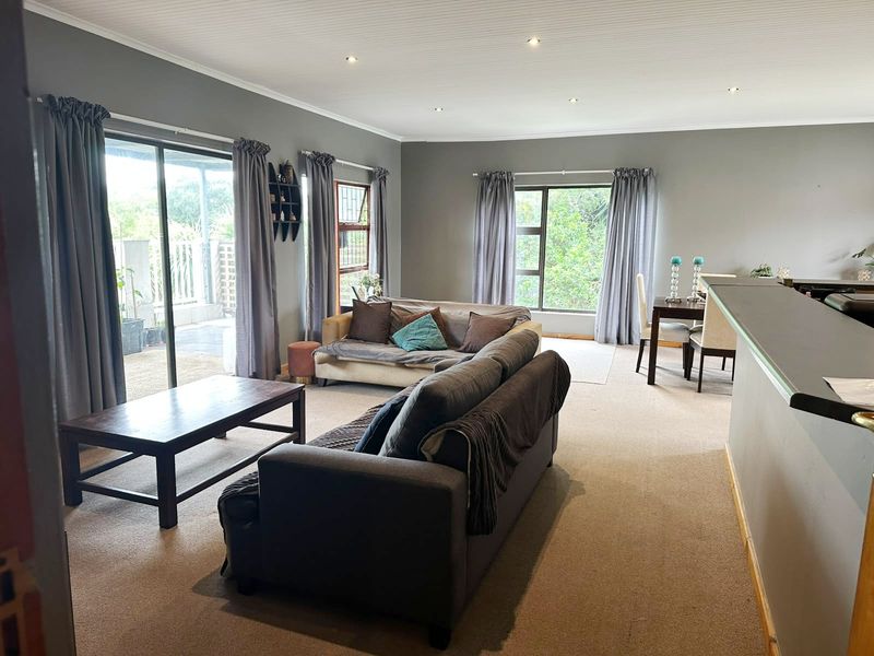 Spacious open-plan living and dining area featuring neutral grey walls, recessed lighting, and large sliding doors providing access to the outdoor space.