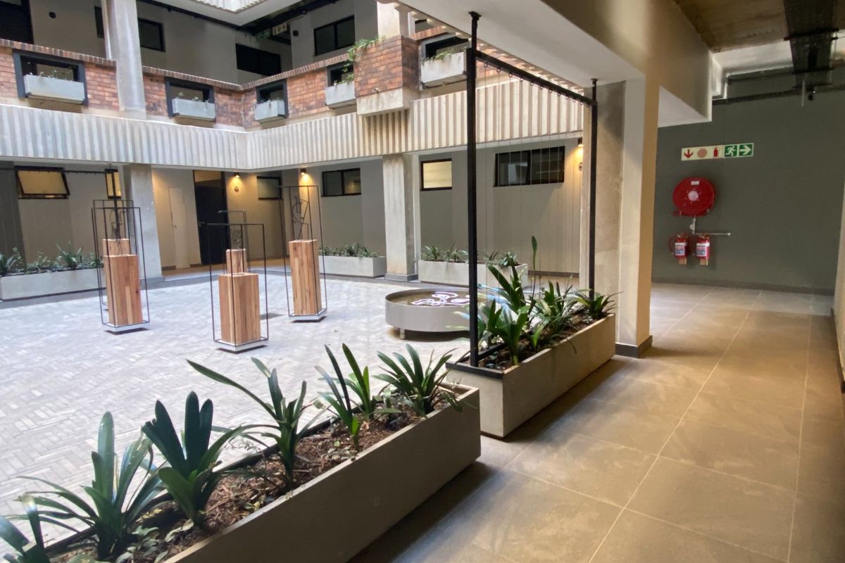 A well-maintained central courtyard featuring brick and concrete architecture, paved flooring, and integrated planters within an apartment complex.