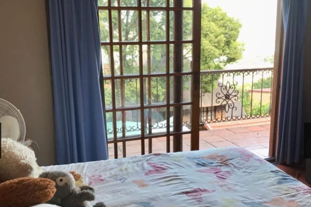 Bedroom featuring a wooden sliding door that opens onto a tiled balcony with decorative wrought iron railings.