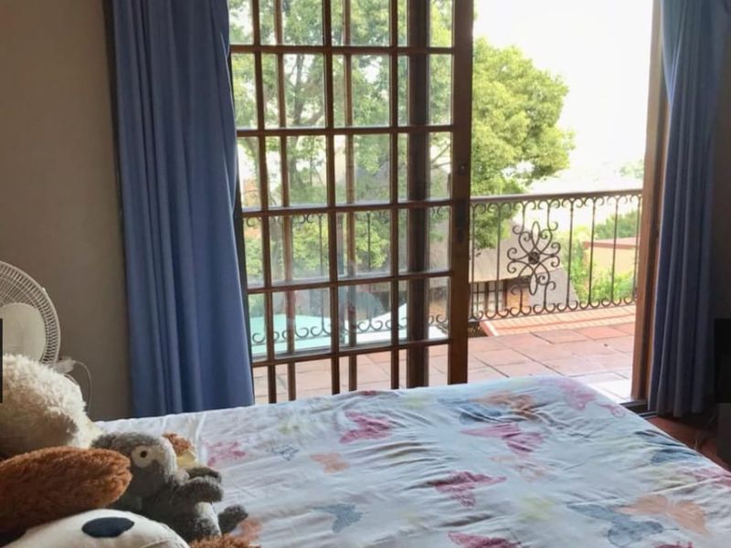 Bedroom featuring a wooden sliding door that opens onto a tiled balcony with decorative wrought iron railings.