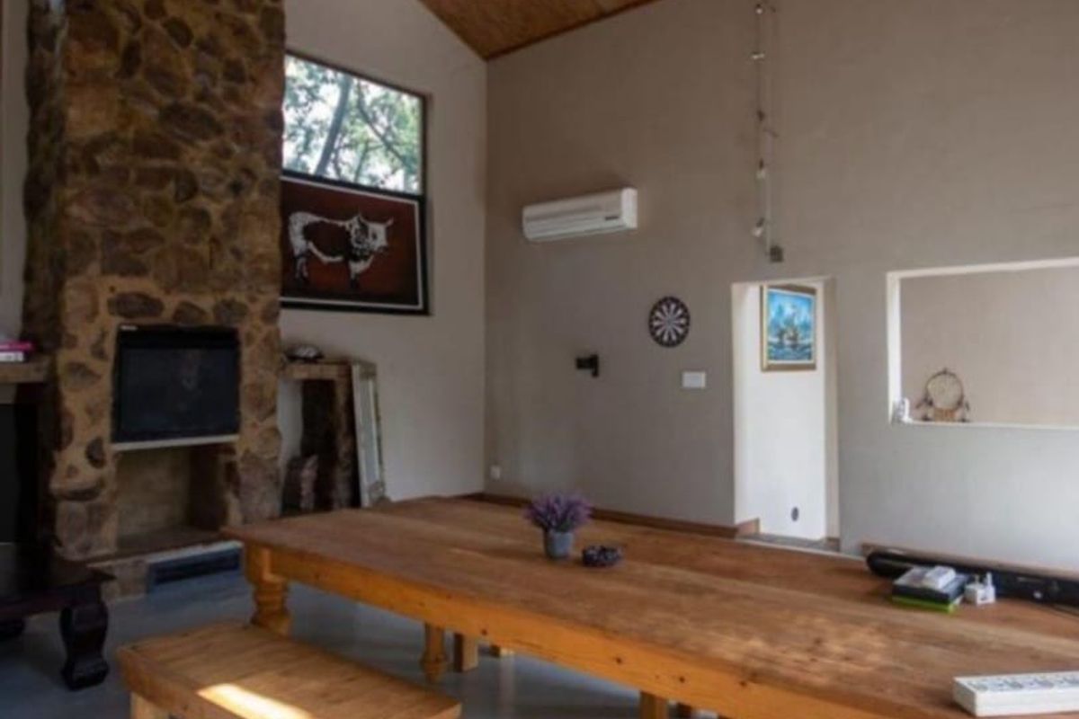 Spacious living area featuring a prominent stone fireplace, vaulted timber ceiling, and split-system air conditioning, creating a warm and rustic atmosphere.