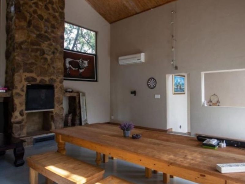 Spacious living area featuring a prominent stone fireplace, vaulted timber ceiling, and split-system air conditioning, creating a warm and rustic atmosphere.