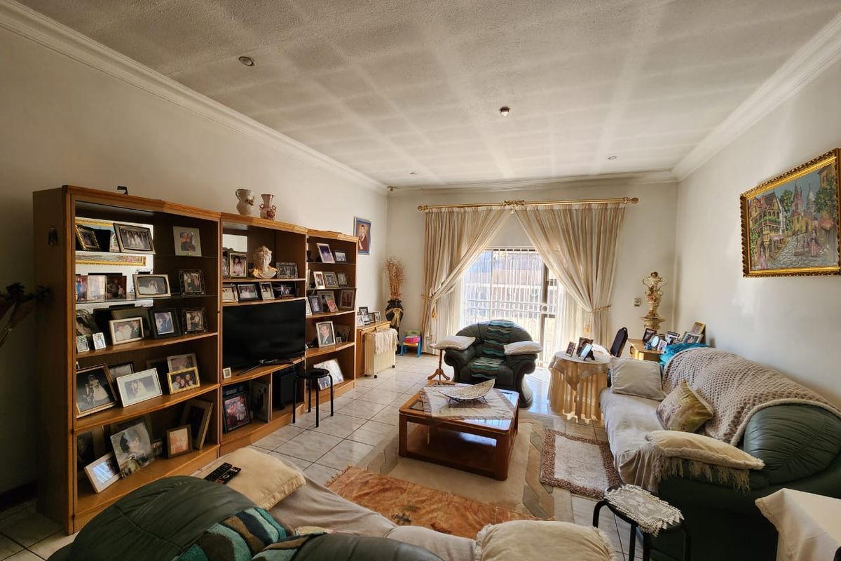 A spacious living room featuring tiled flooring, recessed ceiling lighting, and a large sliding door providing access to the exterior.