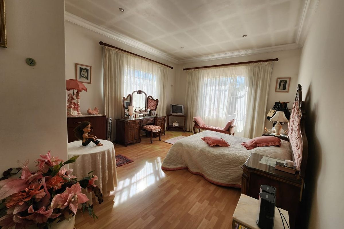Spacious bedroom featuring laminate flooring, recessed ceiling lighting, and large windows with sheer curtains, offering a bright and comfortable living space.