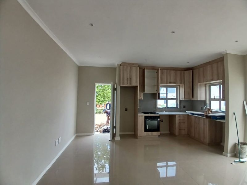 Open plan kitchen and living area featuring modern light wood cabinetry, tiled flooring, and recessed lighting, currently in the final stages of completion.