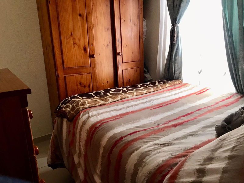 A bedroom featuring a built-in wooden wardrobe and natural light from the window.
