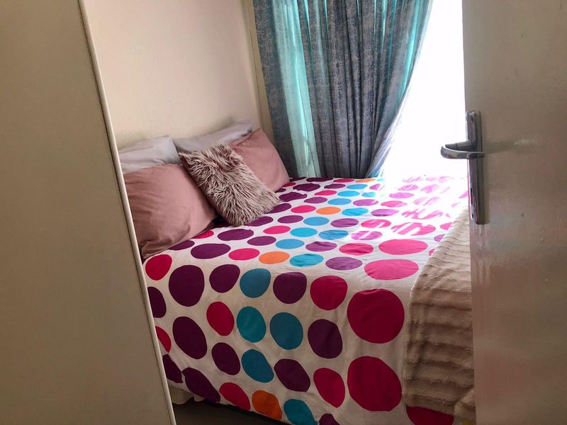 A compact bedroom featuring a built-in cupboard and natural light from the window.