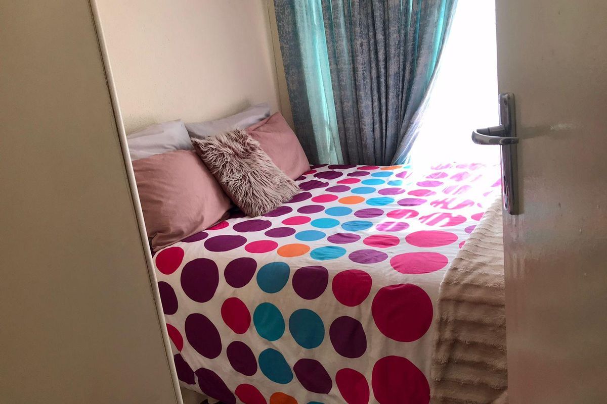 A compact bedroom featuring a built-in cupboard and natural light from the window.