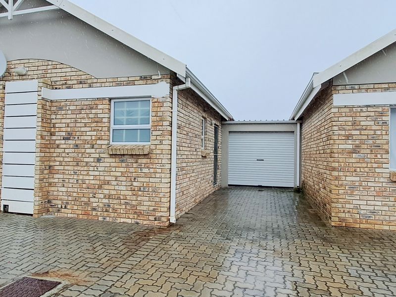 Front exterior view of a face brick townhouse featuring a paved driveway and a single garage.