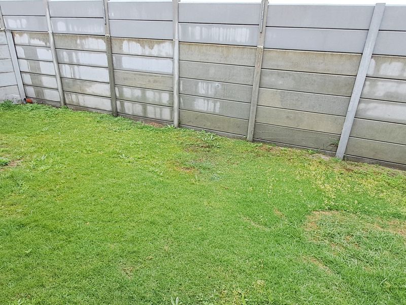 A private rear garden area featuring a lawn and a precast concrete boundary wall.
