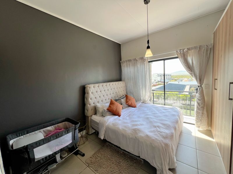 A well-lit bedroom featuring tiled floors, a built-in wardrobe, and a sliding glass door providing access to a private balcony.