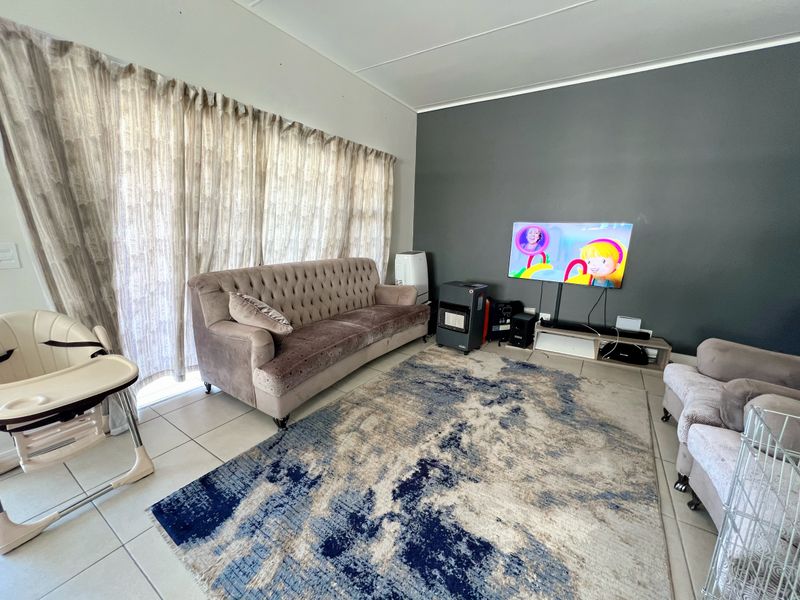 A living room featuring tiled flooring and a large sliding glass door, providing access to natural light.