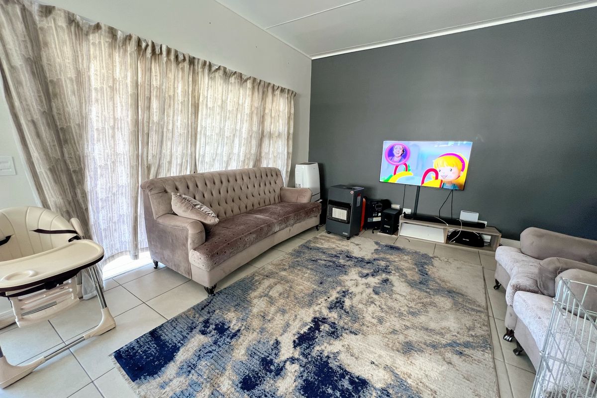 A living room featuring tiled flooring and a large sliding glass door, providing access to natural light.