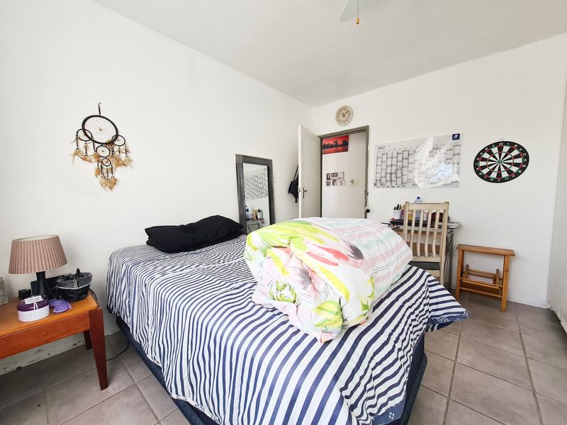 A functional bedroom featuring tiled flooring and a ceiling fan, providing a simple and practical living space.