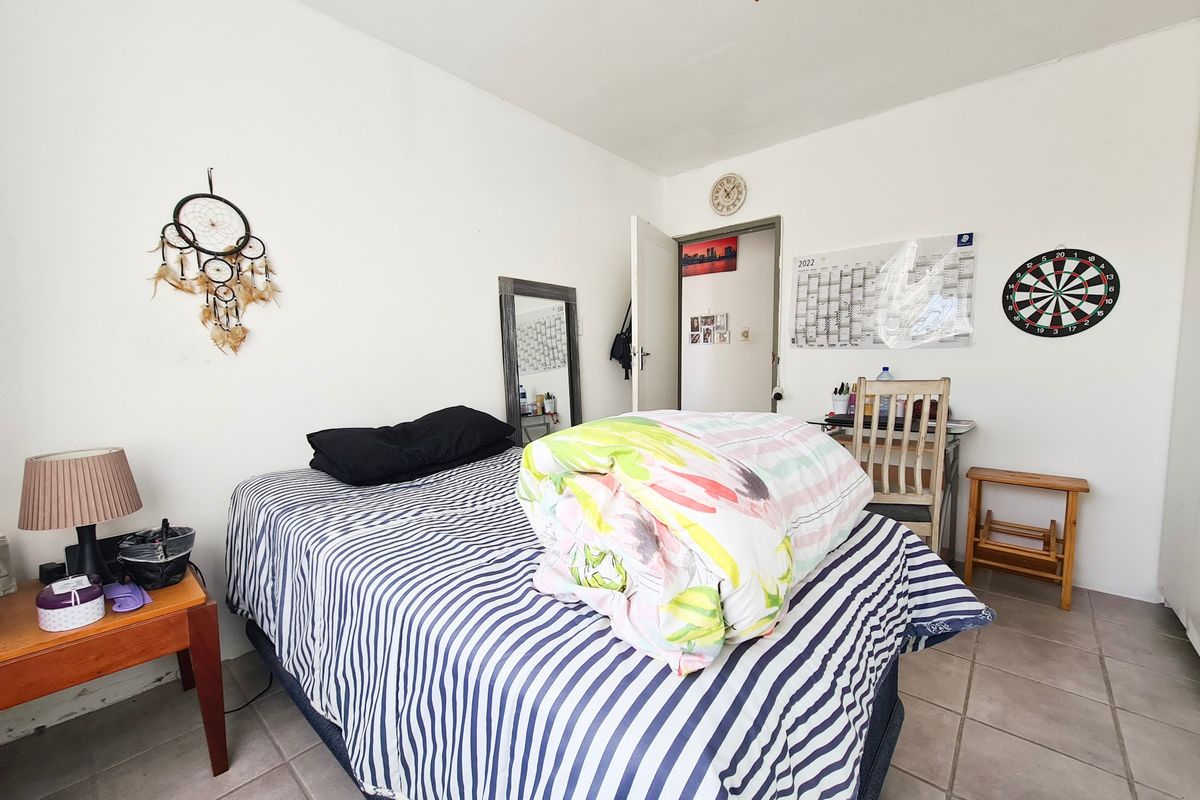 A functional bedroom featuring tiled flooring and a ceiling fan, providing a simple and practical living space.
