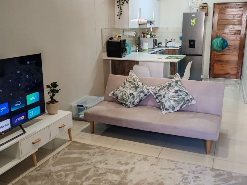 An open-plan living and kitchen area featuring tiled flooring, modern cabinetry, and a functional layout suitable for compact apartment living.