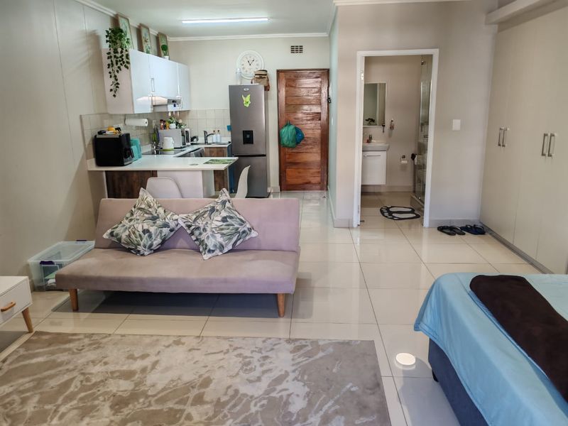 Open-plan studio apartment featuring a compact kitchen, tiled flooring, built-in storage, and an en-suite bathroom with a shower.