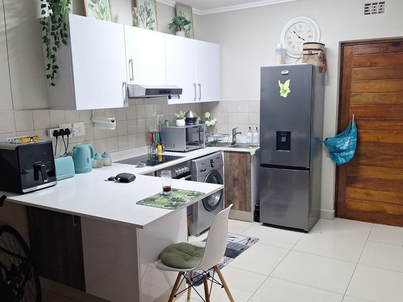 A functional kitchen featuring white cabinetry, tiled backsplash, and tiled flooring, providing a clean and practical workspace for daily cooking and utility needs.