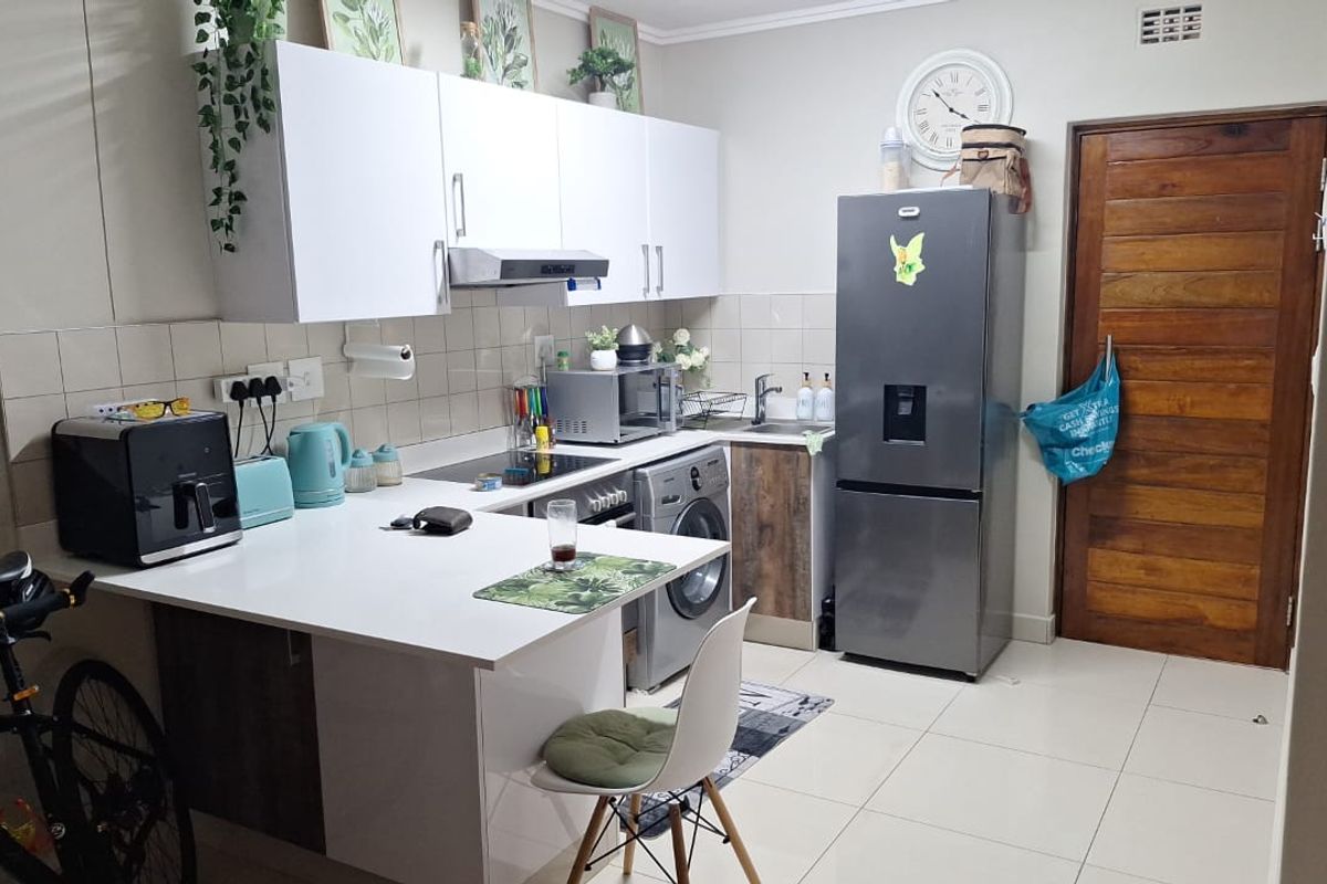 A functional kitchen featuring white cabinetry, tiled backsplash, and tiled flooring, providing a clean and practical workspace for daily cooking and utility needs.