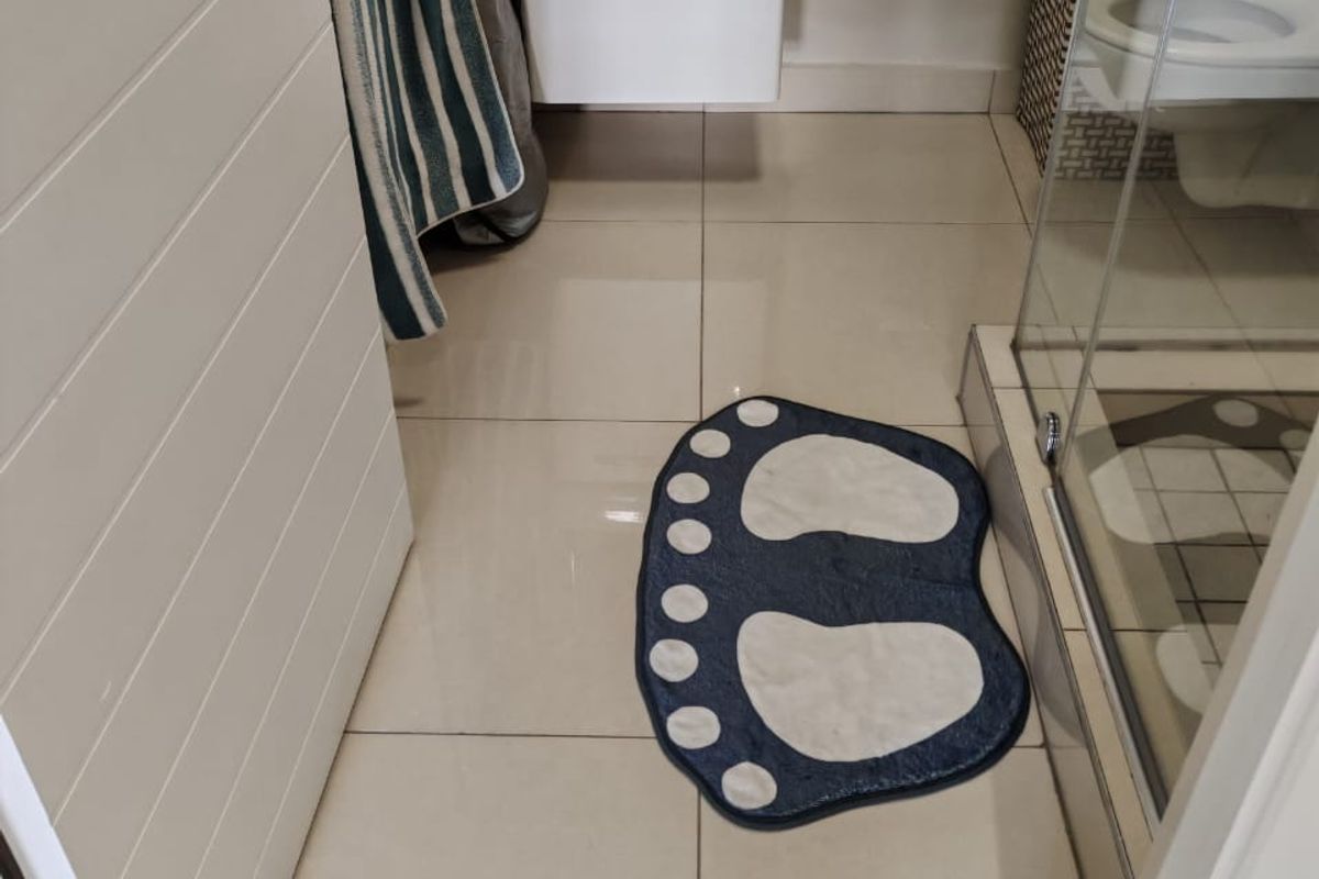 A compact bathroom featuring a wall-mounted vanity, ceramic basin, glass shower enclosure, and tiled flooring.