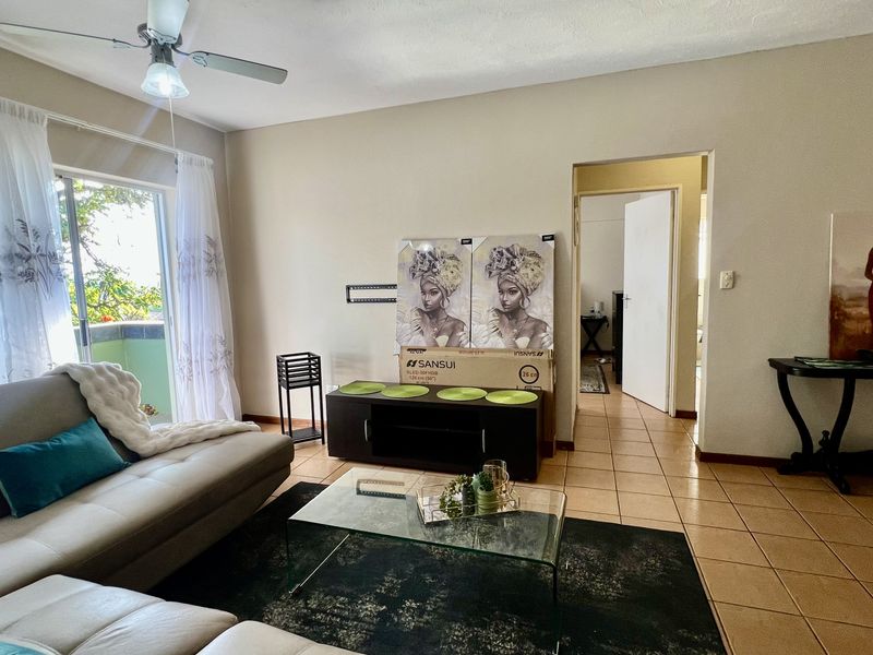 A living room featuring tiled flooring, a ceiling fan, and a sliding glass door providing access to an outdoor area.