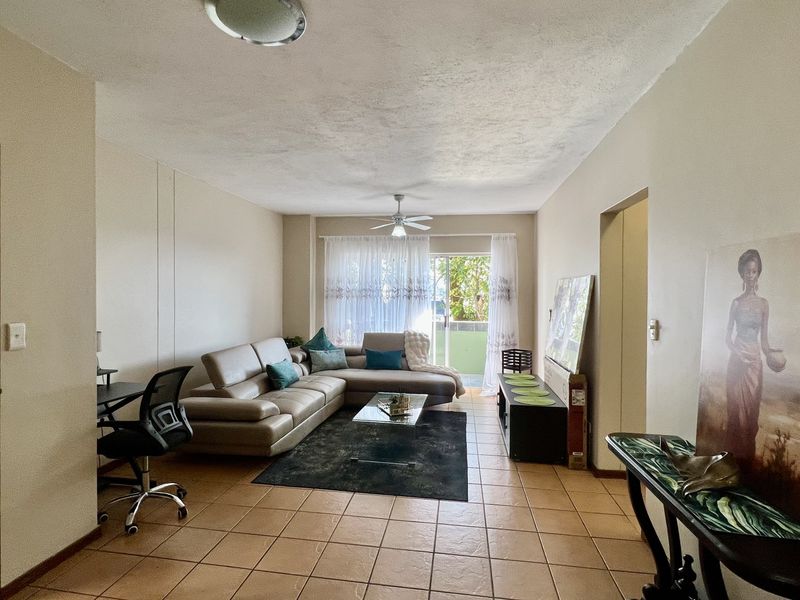 Spacious living room featuring tiled flooring, a ceiling fan, and a sliding glass door providing access to an outdoor area.