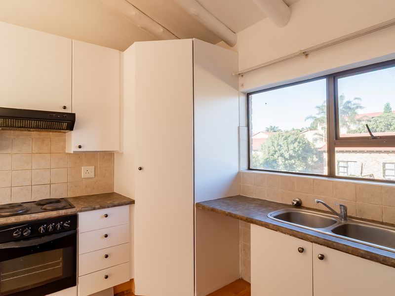 A functional kitchen featuring white built-in cabinetry, laminate countertops, a built-in oven and hob, and a double stainless steel sink with tiled backsplash.