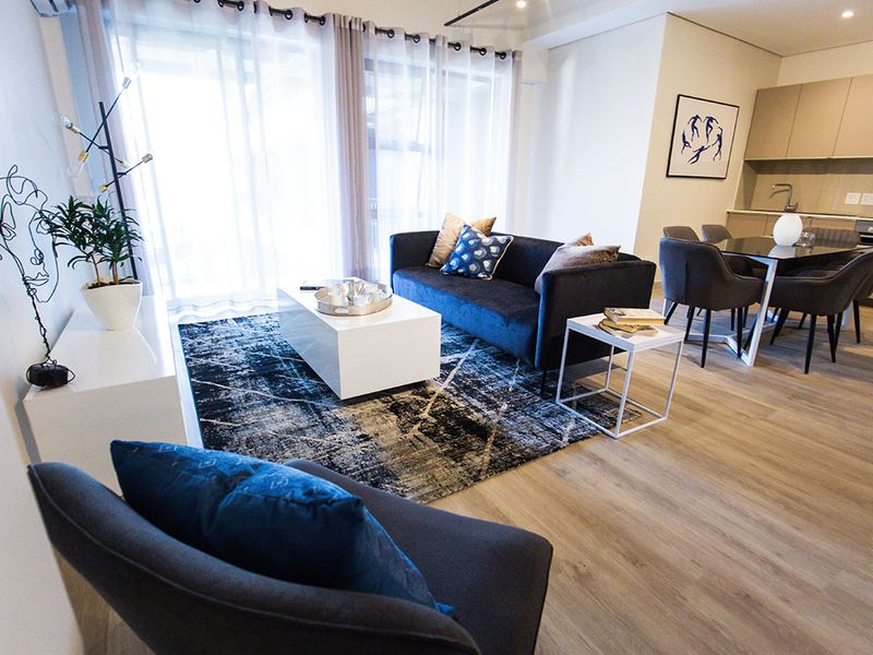 Modern open-plan living and dining area featuring laminate flooring, recessed lighting, and a sleek integrated kitchen with contemporary cabinetry.