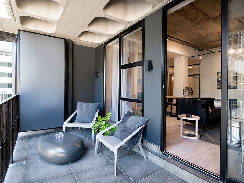 A modern covered balcony featuring dark floor tiles, a distinctive waffle slab ceiling, and large sliding glass doors connecting to the interior living space.