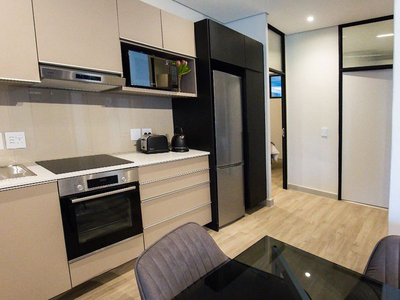 Modern kitchen featuring sleek cabinetry, integrated appliances including an oven and hob, and durable laminate flooring in an open-plan layout.