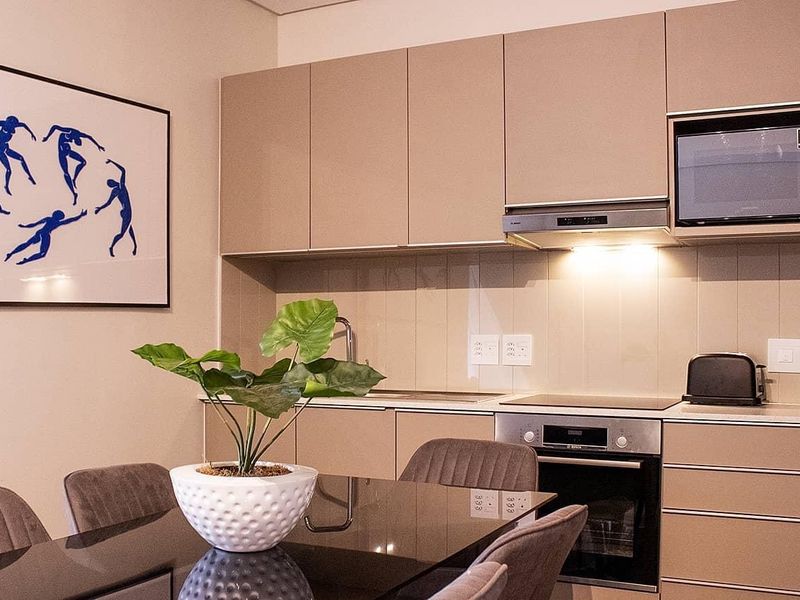 Modern open-plan kitchen featuring sleek built-in cabinetry, integrated appliances, and a clean tiled backsplash, seamlessly connecting to the dining area.