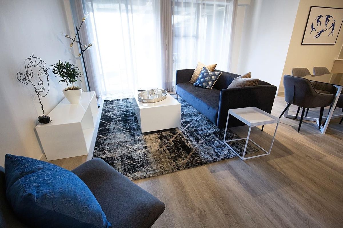 A bright and modern living room featuring light-toned laminate flooring and large sliding glass doors that provide ample natural light.
