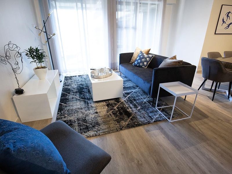 A bright and modern living room featuring light-toned laminate flooring and large sliding glass doors that provide ample natural light.