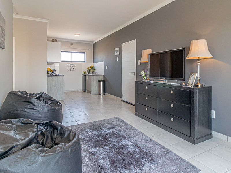 Open-plan living area featuring tiled flooring and a compact kitchen with built-in cabinetry, providing a functional and connected living space.