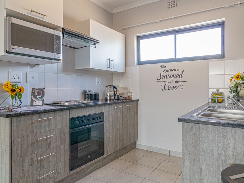 A well-maintained kitchen featuring modern laminate cabinetry, granite countertops, a built-in oven with hob, and a functional double sink setup.