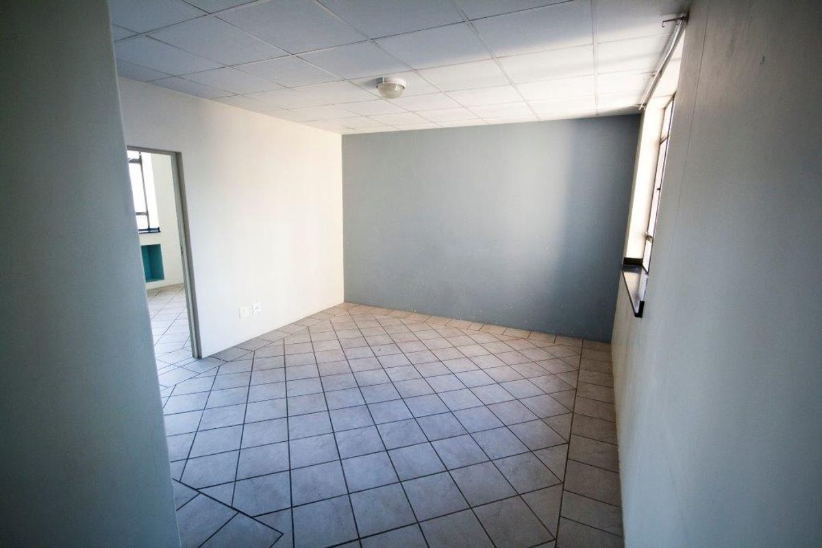 An empty room featuring tiled flooring, a drop ceiling, and a neutral color palette, offering a blank canvas for potential renovation or styling.
