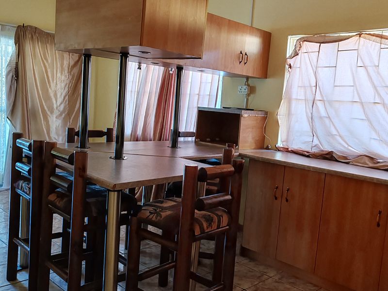 A functional kitchen area featuring laminate cabinetry, a built-in breakfast bar, and ceramic tile flooring, offering potential for a modern update.
