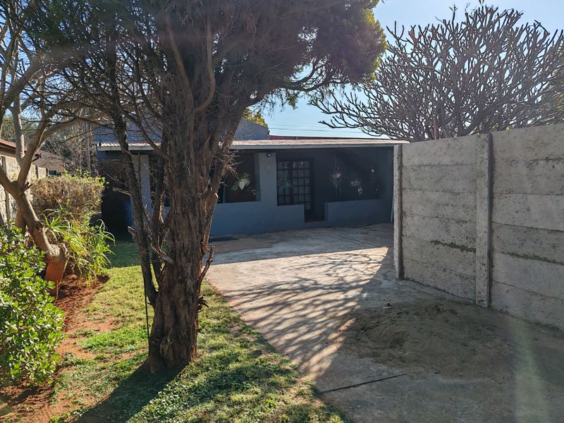 Front exterior view of the cottage featuring a concrete driveway, a covered patio entrance, and a precast concrete boundary wall.