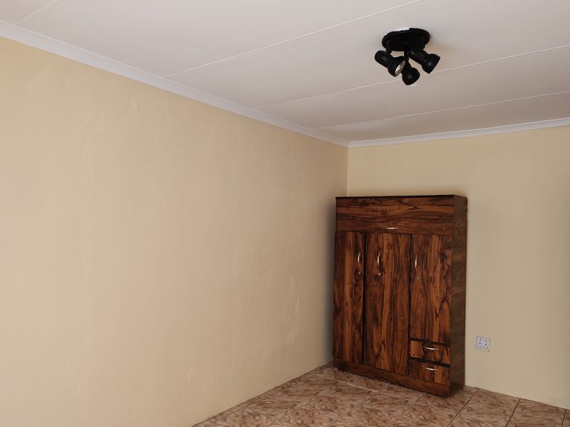 A bedroom featuring tiled flooring, neutral wall paint, and a ceiling-mounted spotlight fixture.