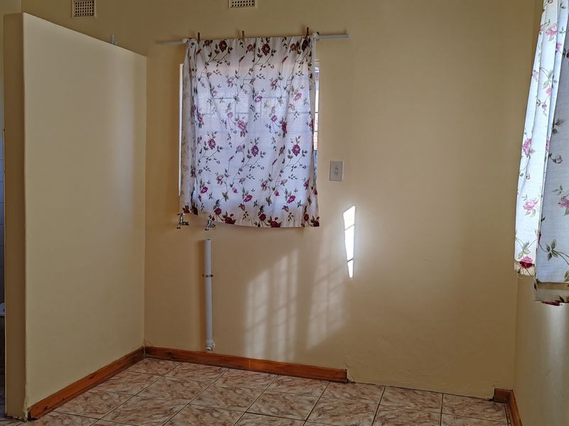 A functional laundry area featuring tiled flooring and dedicated plumbing connections, ready for appliance installation.