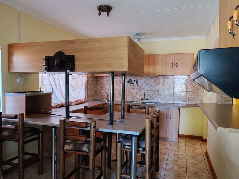 A functional kitchen featuring wood-look cabinetry, tiled backsplash, a breakfast bar, and tiled flooring, offering a practical layout for daily meal preparation.