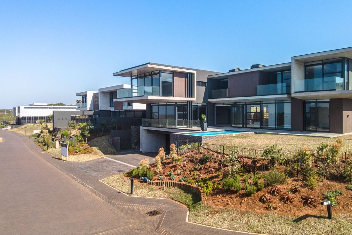 Aerial view of a modern luxury residential estate featuring contemporary architectural design, cantilevered levels, glass balconies, and a private swimming pool.