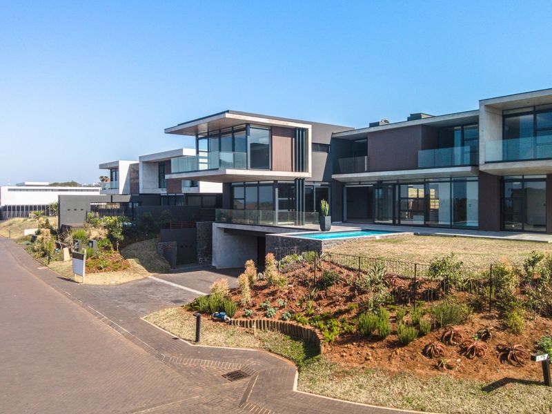 Aerial view of a modern luxury residential estate featuring contemporary architectural design, cantilevered levels, glass balconies, and a private swimming pool.